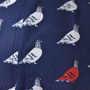 Detail of navy twill fabric featuring white and red pigeon patterns with neat stitching