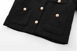 Detailed shot of black jacket with golden embossed buttons and four patch pockets