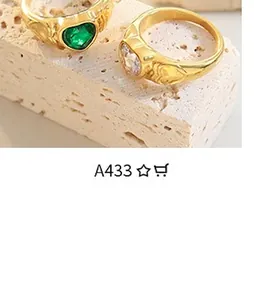 Close-up of vintage gold heart rings with emerald and diamond stones on stone base
