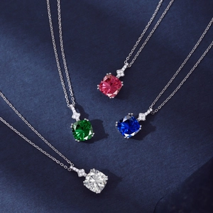 Detailed macro view of silver necklaces with square emerald, ruby, and sapphire gemstones