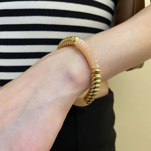 Detail of acrylic bead bracelet with golden spiral texture on model's wrist