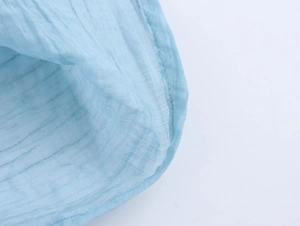 Detailed close-up of light blue pleated fabric texture and stitching on the dress