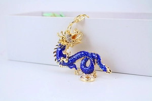 Close-up of golden and blue dragon keychain with sparkling rhinestones on white box