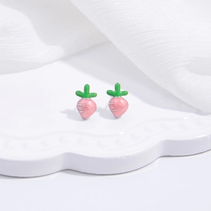 Detail view of pink carrot stud earrings with green leaves on white lace tray