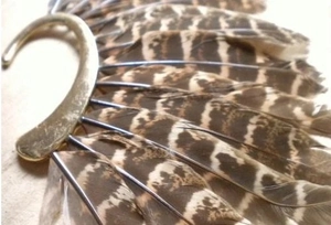Close-up of vintage golden ear hook with brown striped feathers showing detailed texture