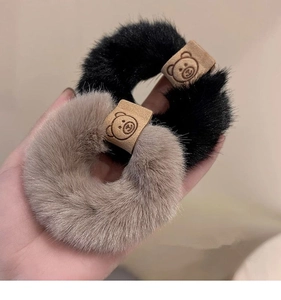 Close-up detail of fluffy plush hair scrunchie with cute bear patch, soft winter hair accessory.