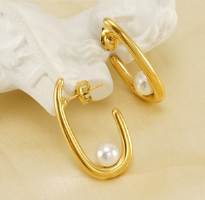 Détail de boucles d'oreilles dorées en U avec perles sur fond de relief blanc élégant