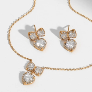 Golden stainless steel jewelry set with bow and heart pendants featuring sparkling zircons