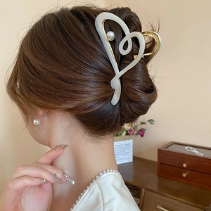 Détail d'une grande pince à cheveux cœur vintage en acrylique avec perle sur modèle