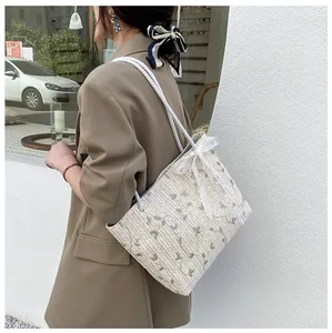 Close-up of summer straw tote bag with floral embroidery and white lace bow detail