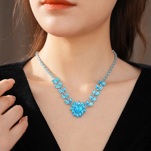 Close-up of model wearing heart-shaped blue crystal necklace with silver leaf accents