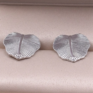 Vista macro degli orecchini a foglia d'argento con trama fine su seta lucida