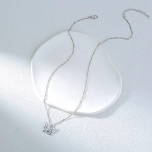 Detail of silver butterfly pendant necklace with zircon on white ceramic tray