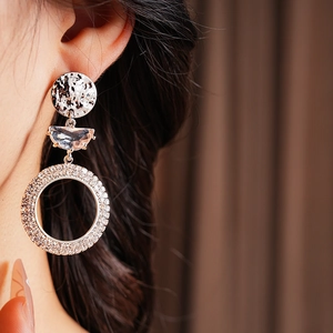 Close-up of golden moon hoop earrings with hammer texture and sparkling crystals on model