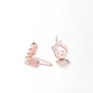 Macro detail of rose gold flame earrings showing irregular cutout design and metal texture