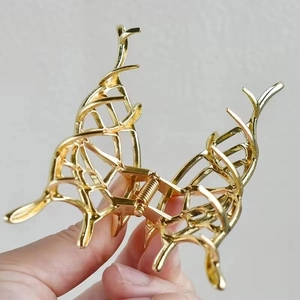 Close-up of golden hollow metal hair claw clip with intricate butterfly wing design