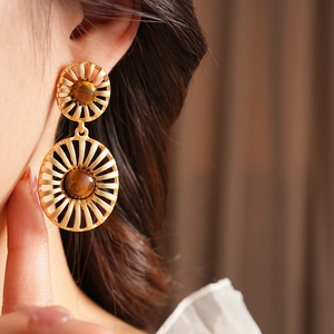 Detailed view of vintage gold textured earrings with oval tiger eye stones on model