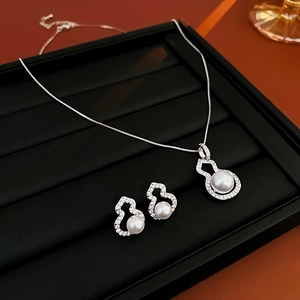 Detailed view of silver gourd-shaped necklace and earrings set with pearls and zircons