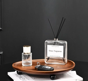 Detail of a square reed diffuser and walnut wooden tray with elegant black spherical legs