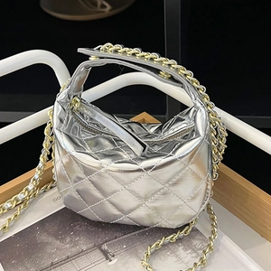 Mini silver quilted crossbody bag with gold chain strap on modern geometric stand