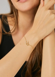 Detailed close-up of double interlocking circles gold bracelet with cubic zirconia on model