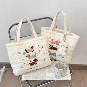 Close-up of cute cat and dog embroidery on cream quilted tote bags with plush charm