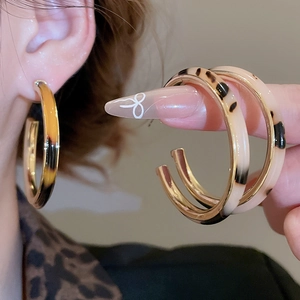 Detailed view of large C-shaped tortoiseshell acrylic earrings with gold metallic lining