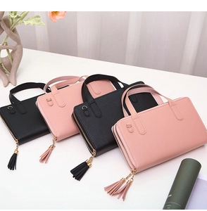 Detail of double zipper wallets in black and pink with stylish leather tassels and handles