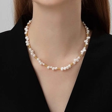 Detailed view of elegant freshwater pearl necklace with gold beads on female model neck