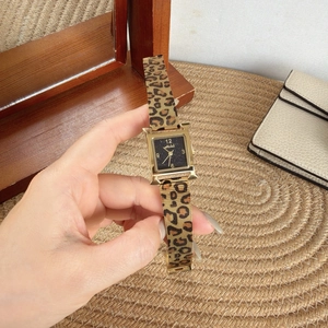 Close-up of a gold H-shaped watch with black glitter dial and leopard print mesh band