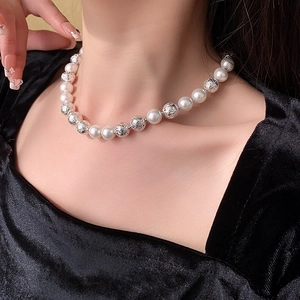 Close-up of minimalist necklace with white pearls and silver hollow beads on a neck
