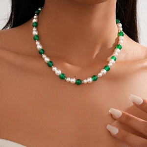 Detail of beaded necklace with green agate-style beads and white pearls on a model