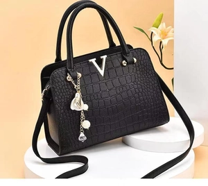 Detail of black crocodile embossed leather handbag with silver V logo and pearl charm