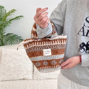 Detailed view of plush winter handbag featuring knitted snowflake patterns and furry texture