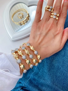 Detail of stacked gold bangles and rings with square studs and zircon discs on a model
