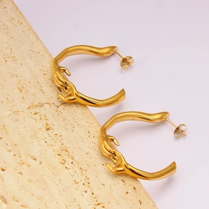 Boucles d'oreilles artistiques en acier inoxydable doré de forme C sur pierre texturée