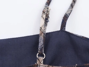 Detail view of navy blue fabric with plaid straps and silver metal ring connector