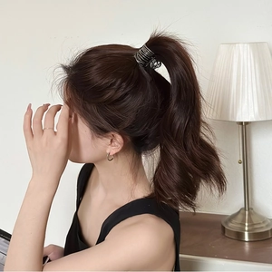 Detail of high ponytail secured with a spiral metallic hair clip on dark brown hair
