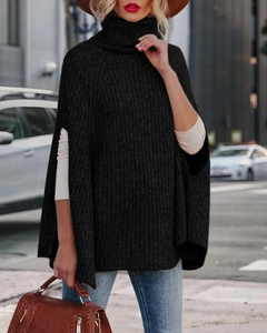 Dettaglio del collo alto in maglia grossa su un elegante poncho a mantella nera da donna