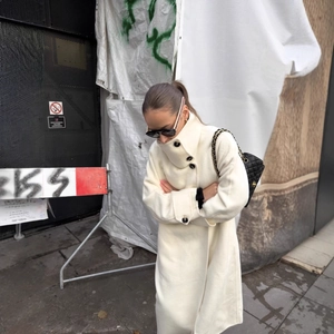 Elegant white wool trench coat with stand collar and single-breasted design on a model