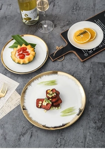 Close-up of luxury gold-rimmed ceramic plates on a grey textured table with elegant decor