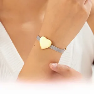 Close-up of golden heart pendant on stainless steel mesh strap bracelet for women