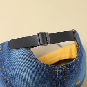 Blue denim baseball cap back view featuring adjustable leather strap and yellow lining
