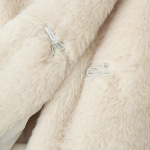 Detailed close-up of cream faux fur coat featuring metallic hidden hook and eye closures
