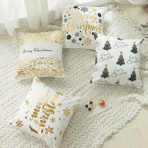 White Christmas pillow covers with gold snowflake and reindeer prints on plush carpet