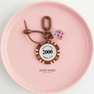 Detail of Monte Carlo poker chip keychain with red translucent dice on pink plate