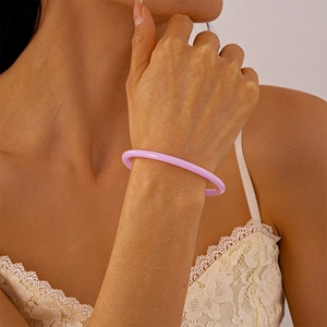 Détail du bracelet rond minimaliste en acrylique rose-violet sur le poignet d'une femme
