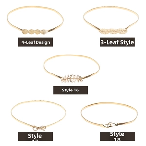 Detail of gold elastic metal belts with leaf, feather, and bow charms for dresses