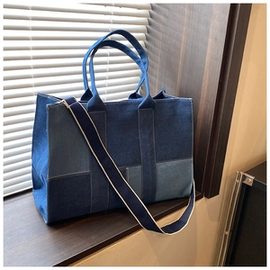 Detailed texture of blue denim patchwork tote bag with white stitching and shoulder strap