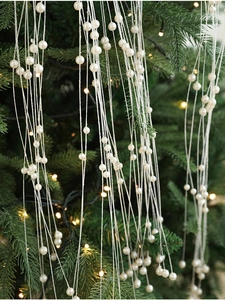 Gros plan d'une guirlande de perles ivoire sur un sapin de Noël avec lumières chaudes
